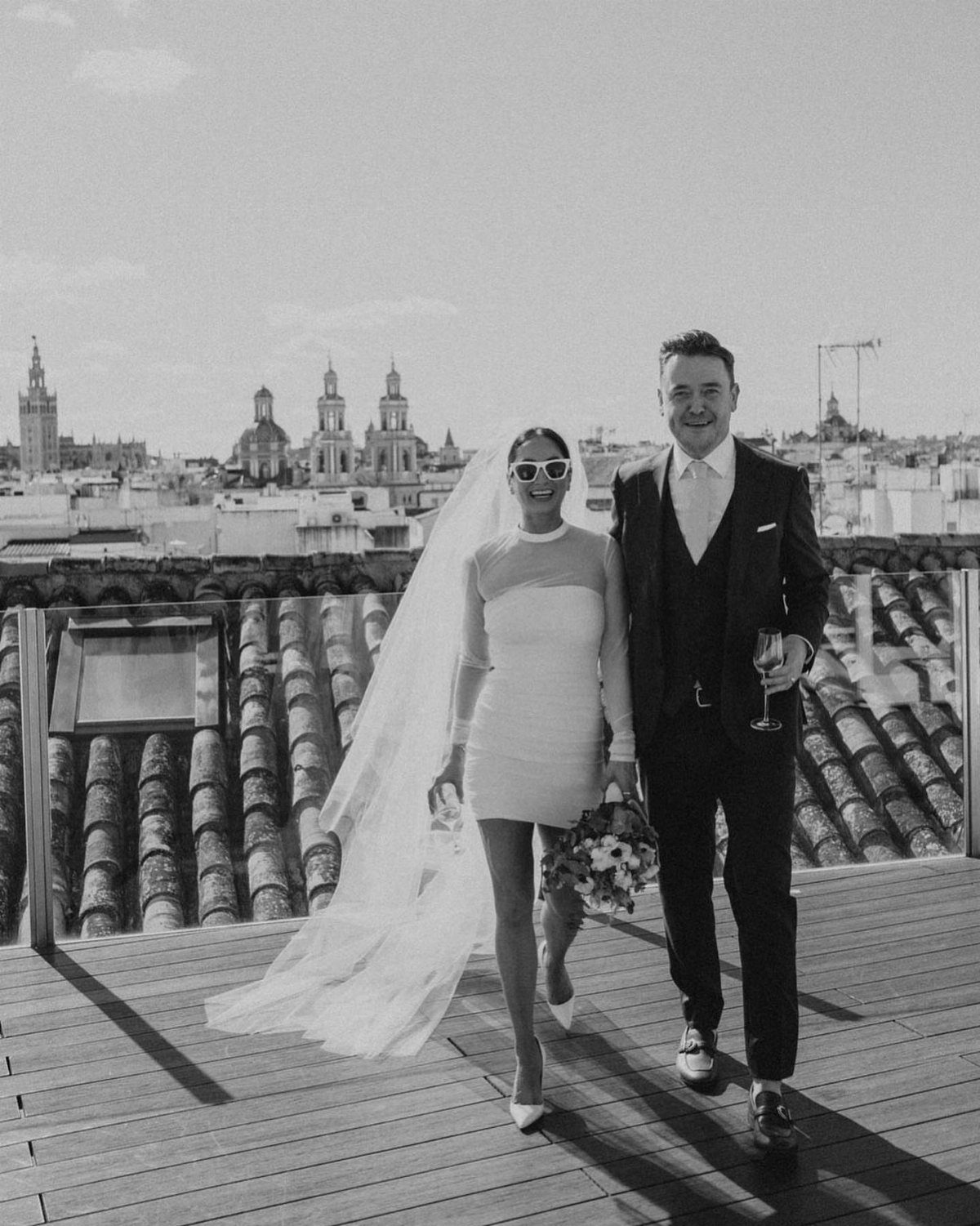 Bride in a short white mini wedding dress and groom on a rooftop.