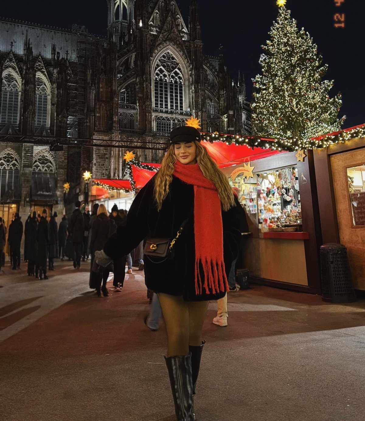 Woman in black coat and red scarf at a winter night market