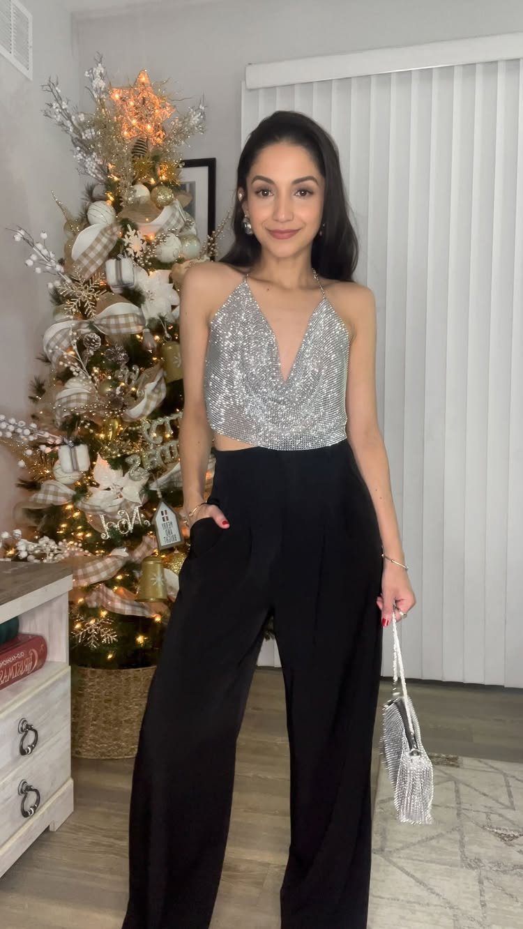 Woman in silver sequin top and black trousers holding a sparkly silver handbag.