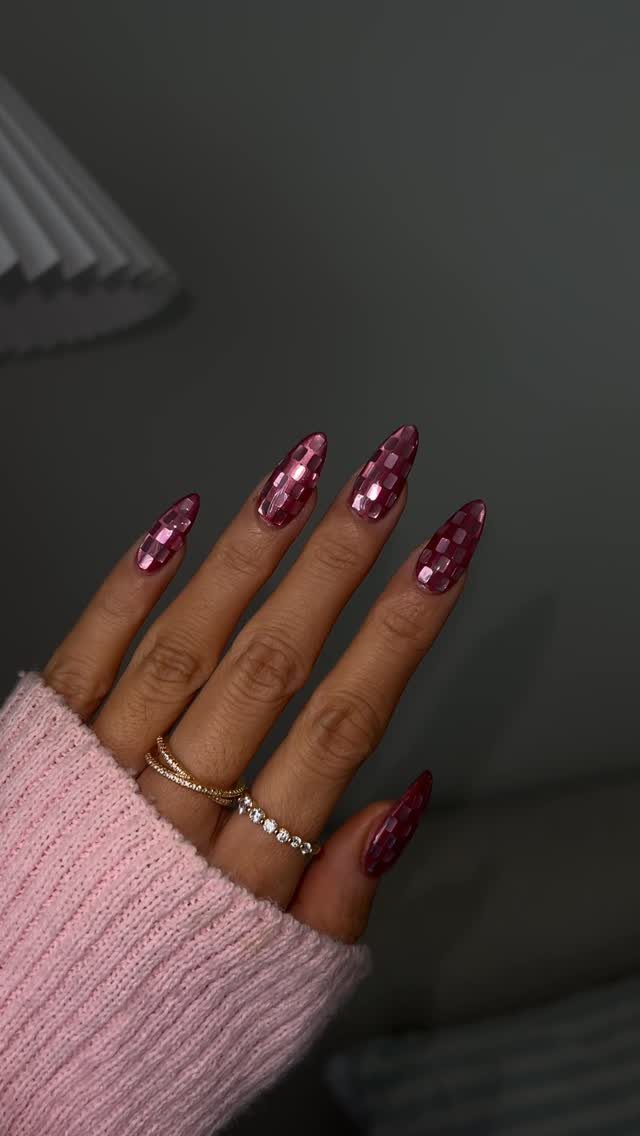 Almond-shaped nails with pink mirrored disco ball effect and gold rings.