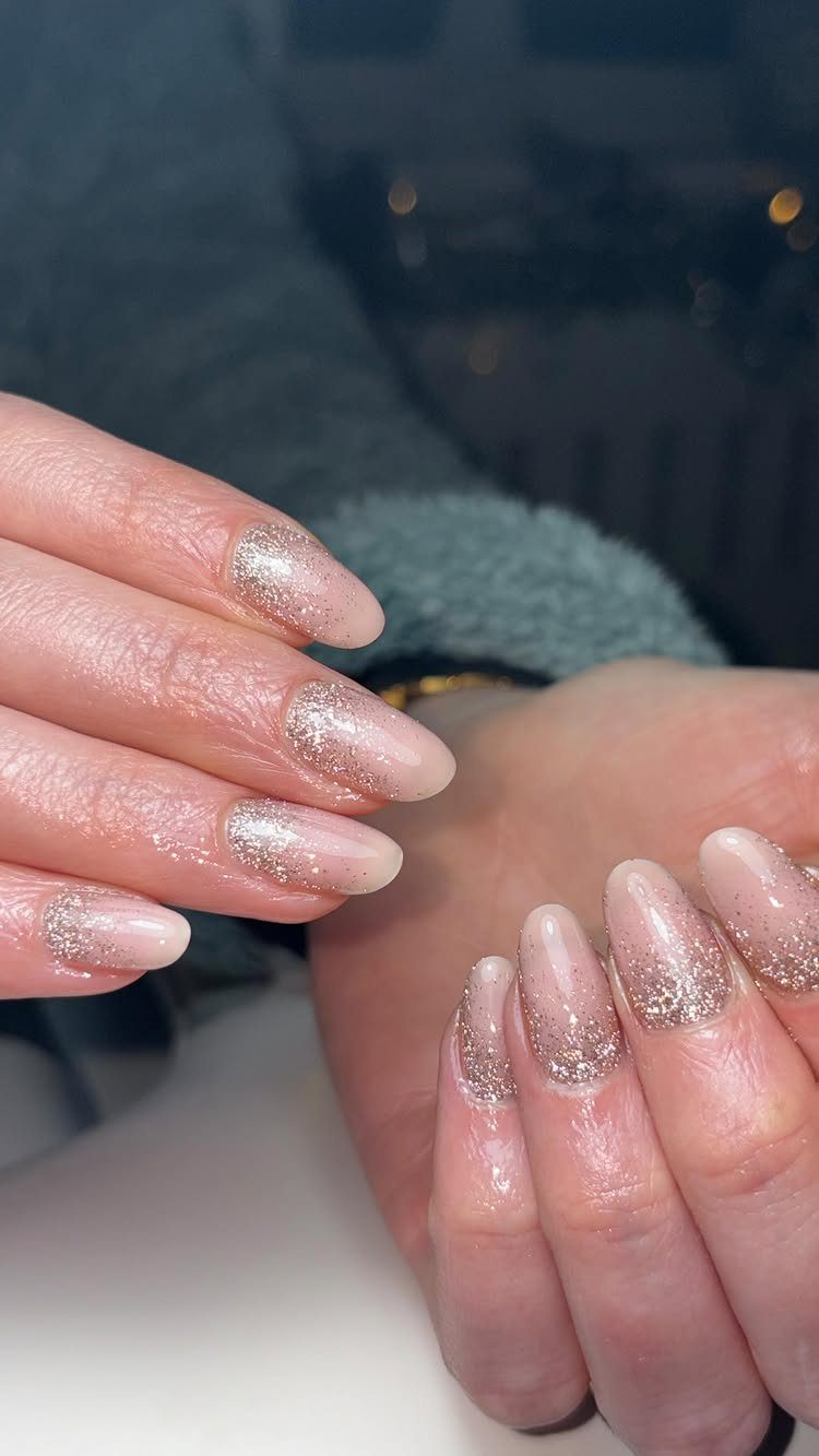 Almond-shaped nails with a shimmering gold glitter ombré effect fading toward the base.