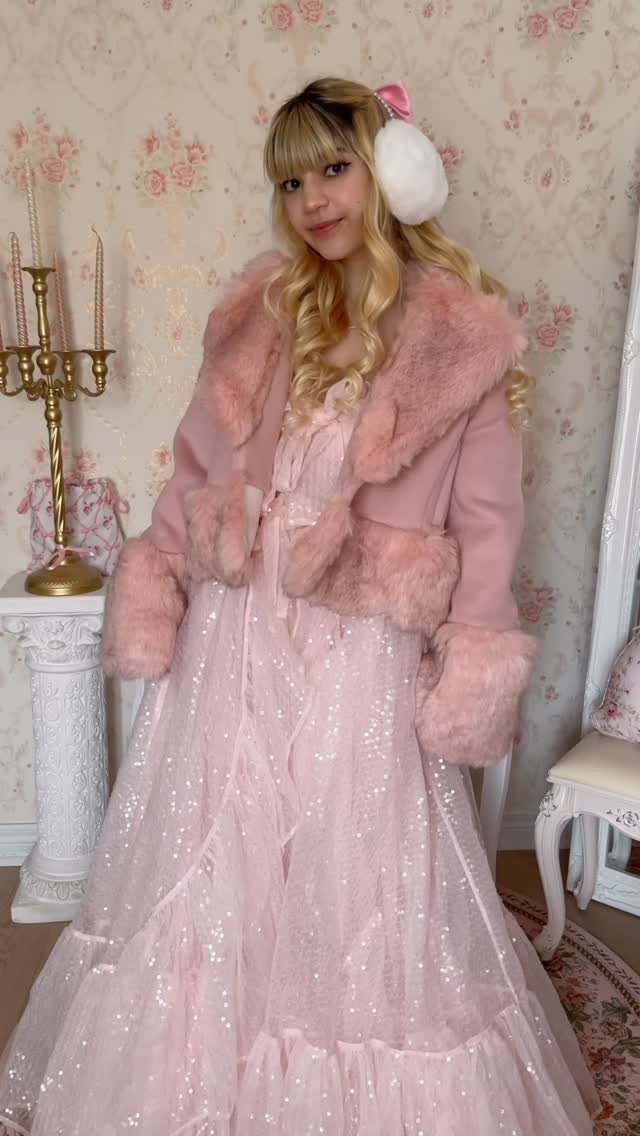 Woman in a sparkly pink gown and faux-fur jacket in a floral room.