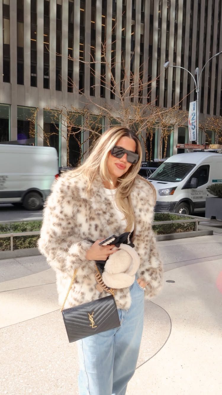 Woman in a fluffy faux fur coat and light blue jeans in New York.