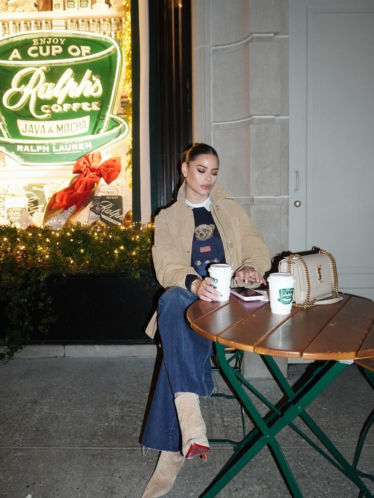 Woman in tan jacket and navy sweater sitting at a New York cafe.