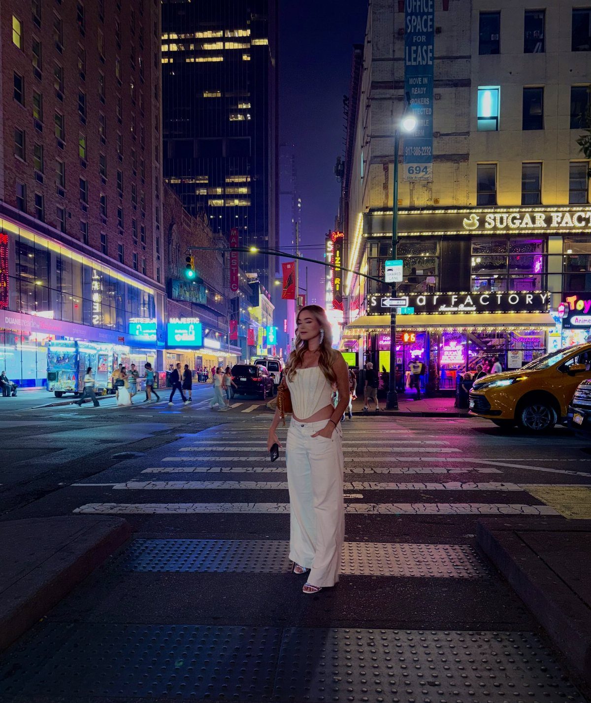 Woman in white crop top and wide-leg trousers standing in New York City street
