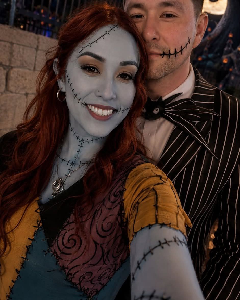 Couple dressed as Sally and Jack Skellington with blue skin and stitch makeup.