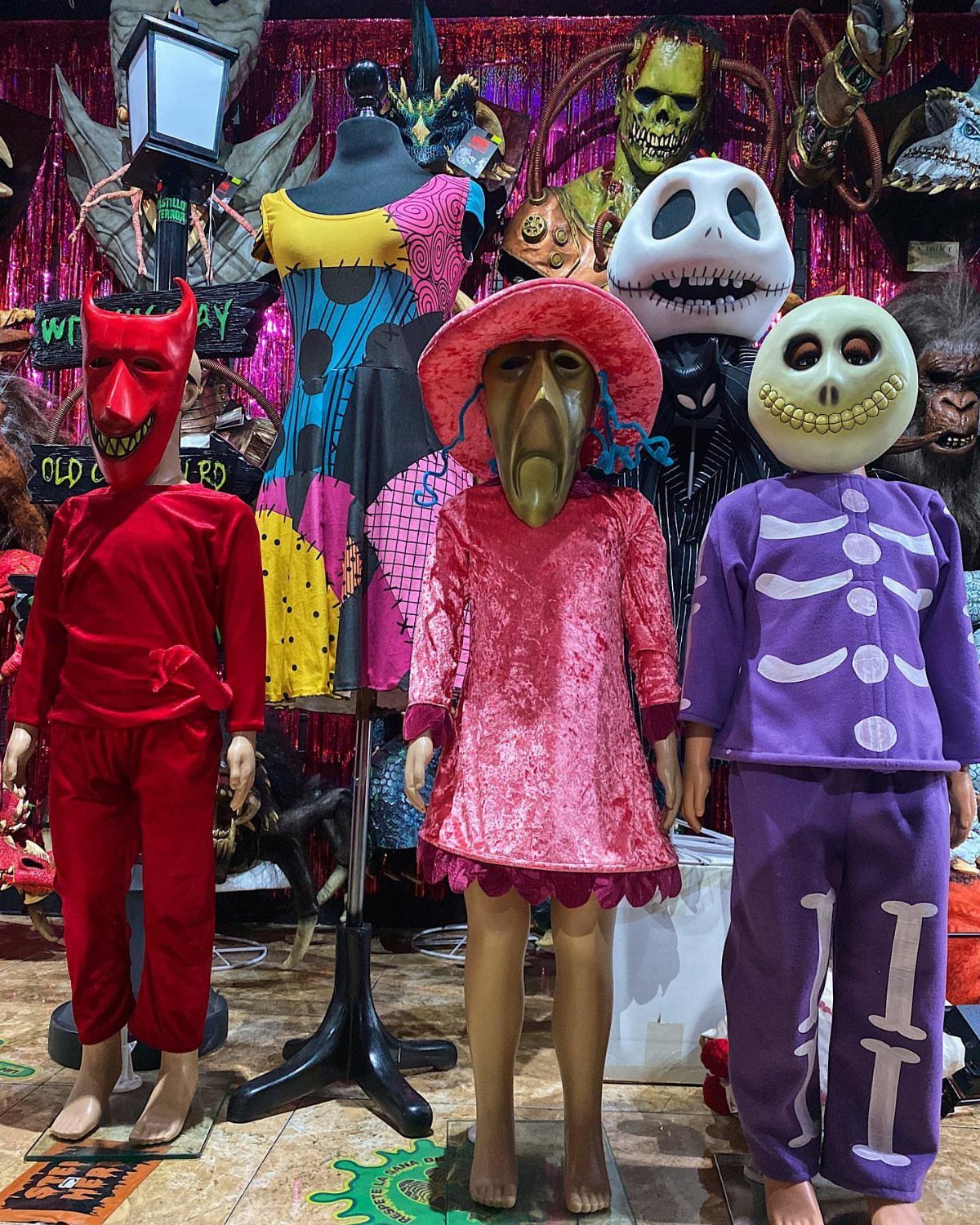 Three mannequins wearing Lock, Shock, and Barrel costumes in a spooky costume shop.