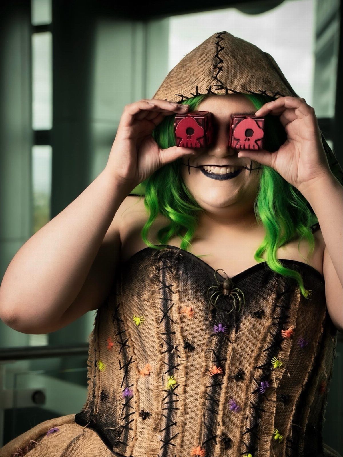 Person in an Oogie Boogie costume holding red dice over their eyes.