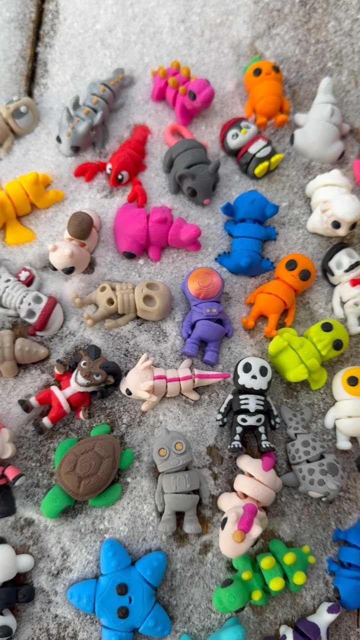 Small colorful miniature figurines scattered on a white textured surface.