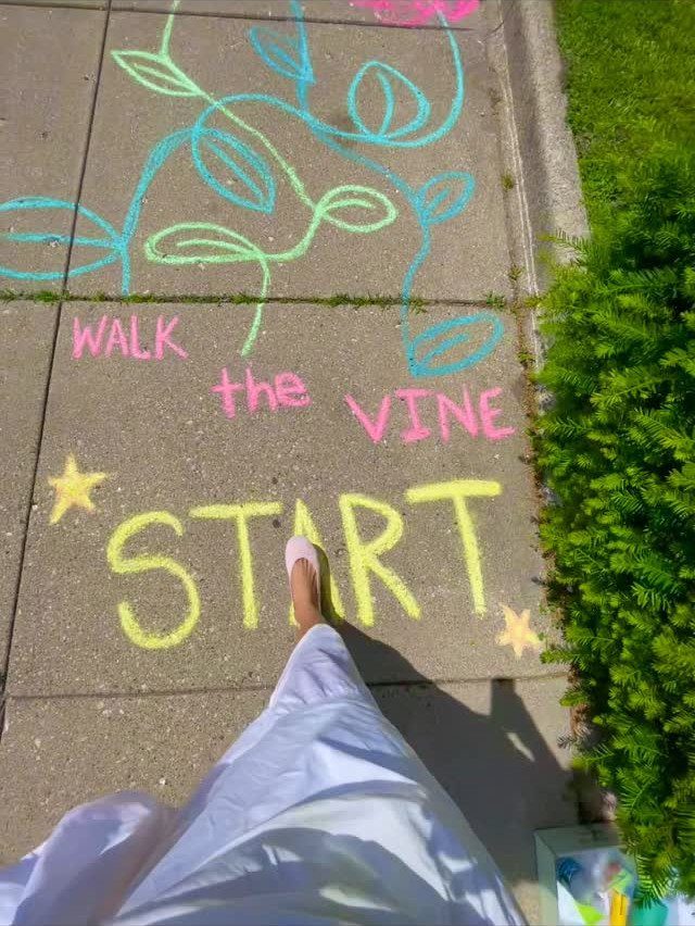 Colorful chalk drawings of a vine and start line on a concrete sidewalk.