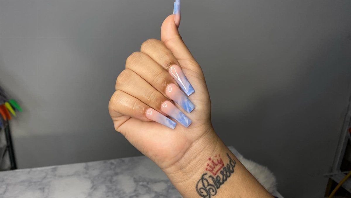 Hand with long square nails featuring a white and blue ombre gradient design