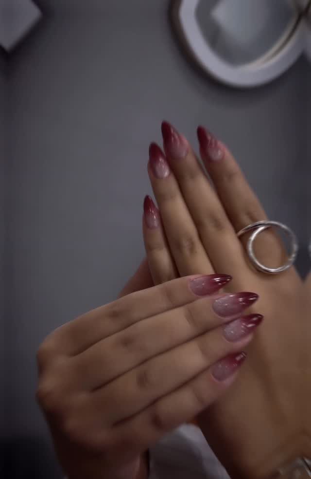 Long almond-shaped nails with a red and white ombre gradient on two hands.
