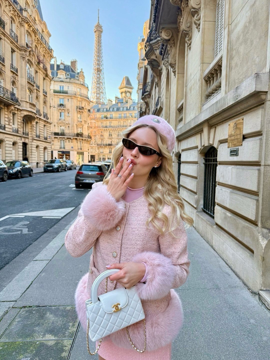 Woman in pink beret and faux-fur coat posing on a Paris street.