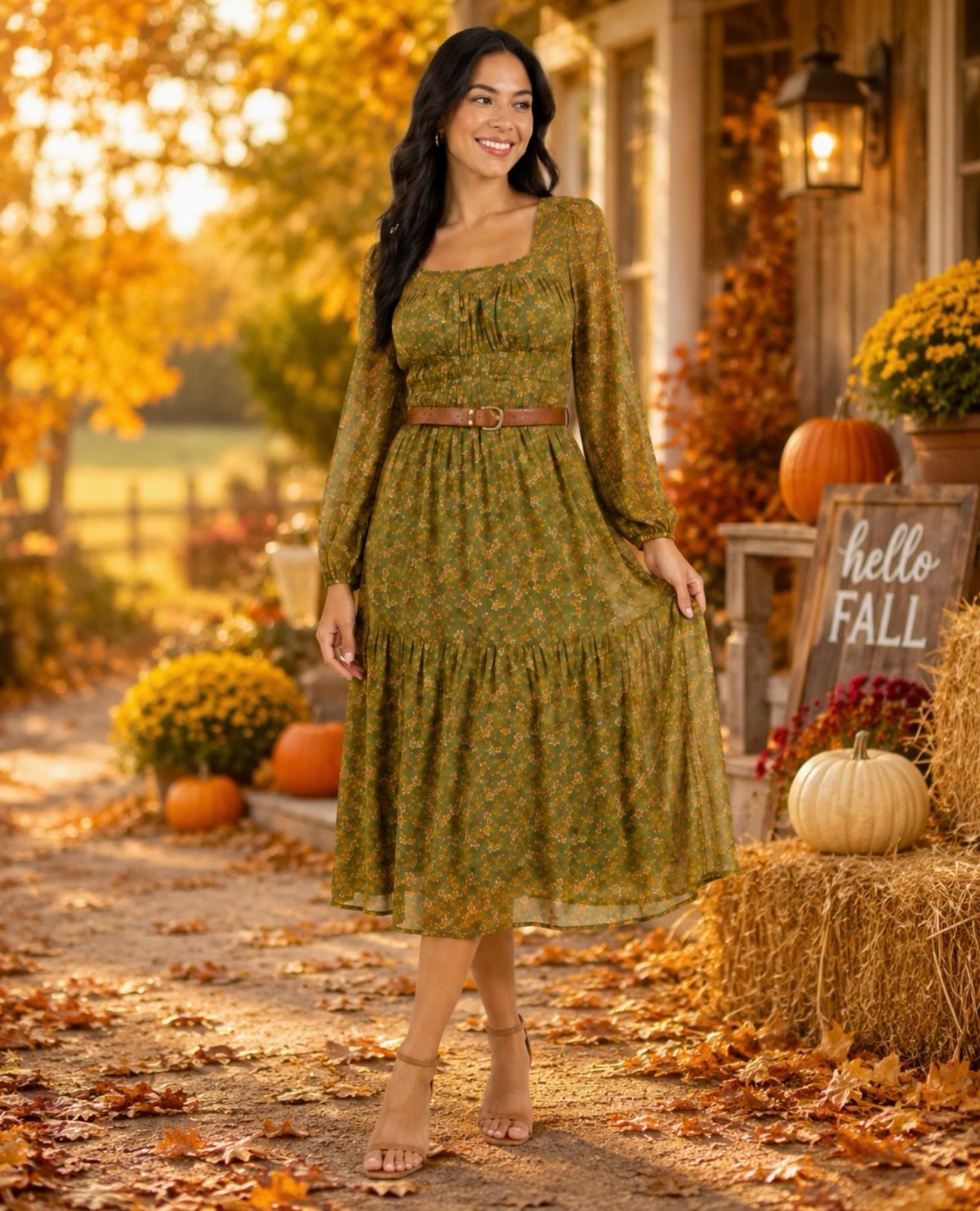 Woman in olive green floral midi dress standing among pumpkins and autumn leaves.
