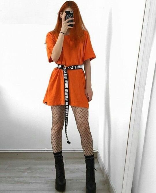 Person in orange dress and black fishnet tights posing for a mirror selfie.