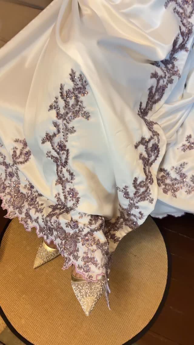 White satin dress with purple embroidery and sparkly silver high heel shoes.