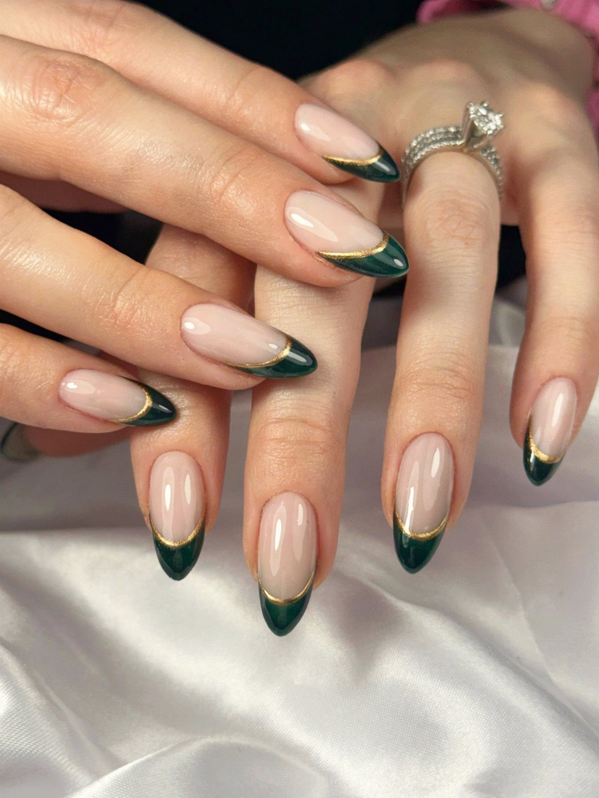 Almond nails with emerald green French tips and thin gold foil accents.