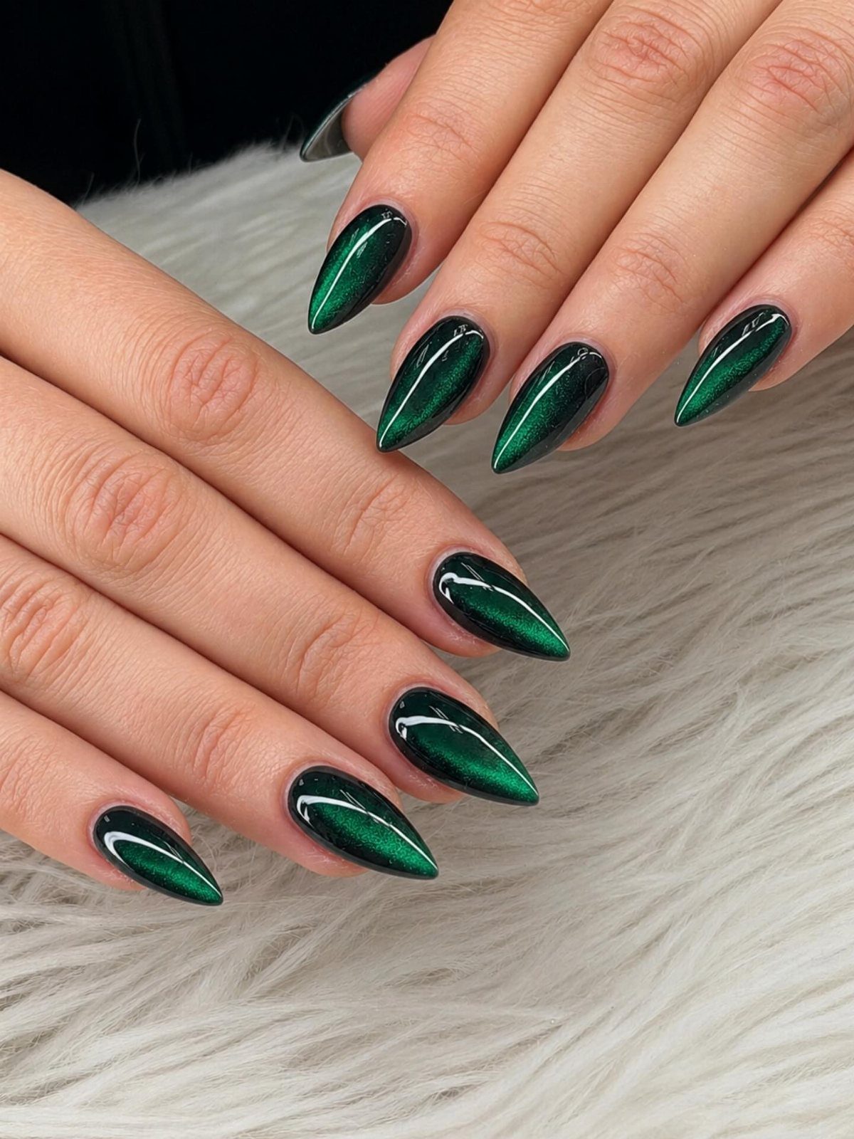 Emerald green chrome almond nails with thin white curved line accents on white fur.