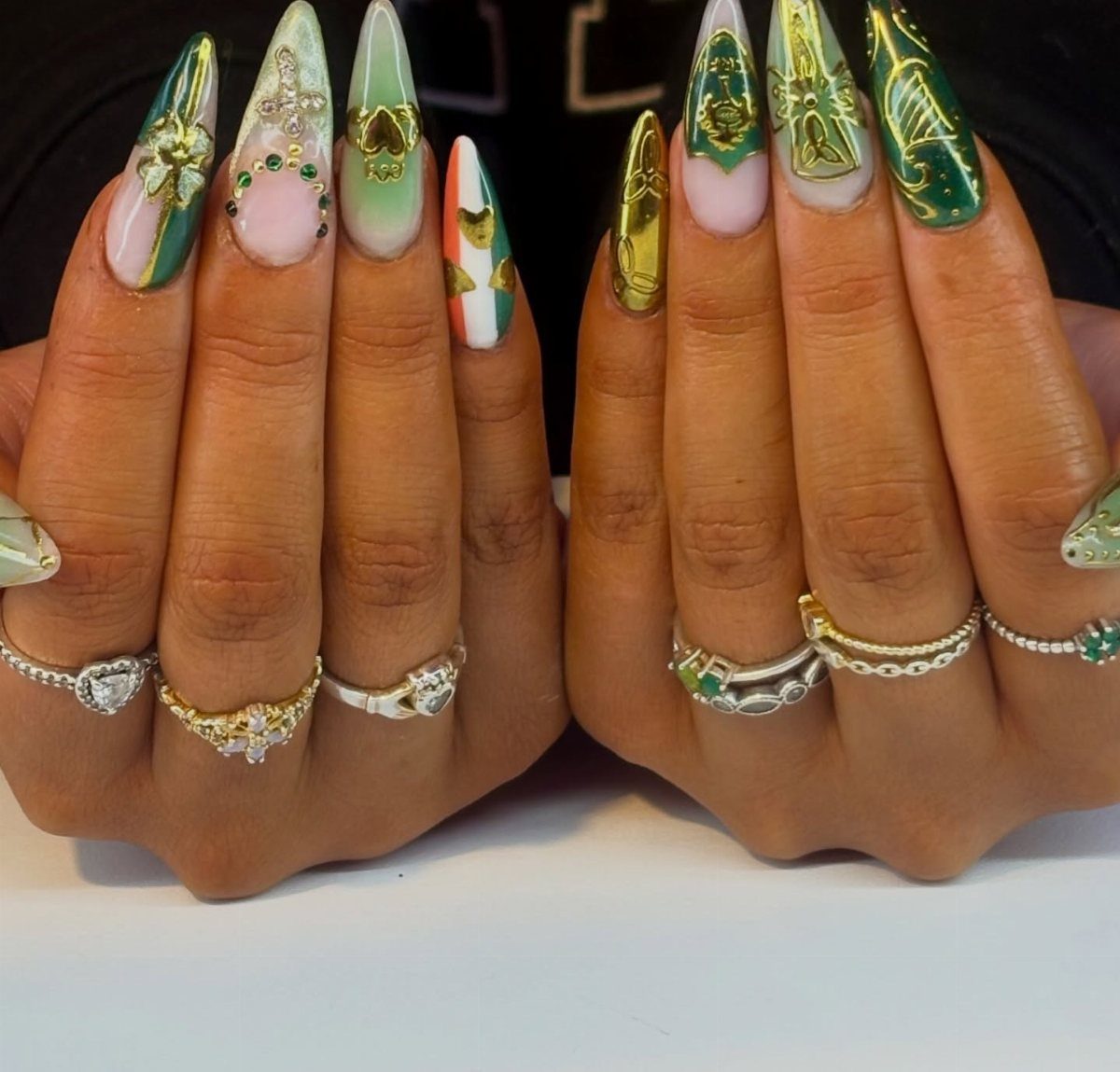 Almond nails with green and gold nail art featuring shamrocks and Irish symbols.