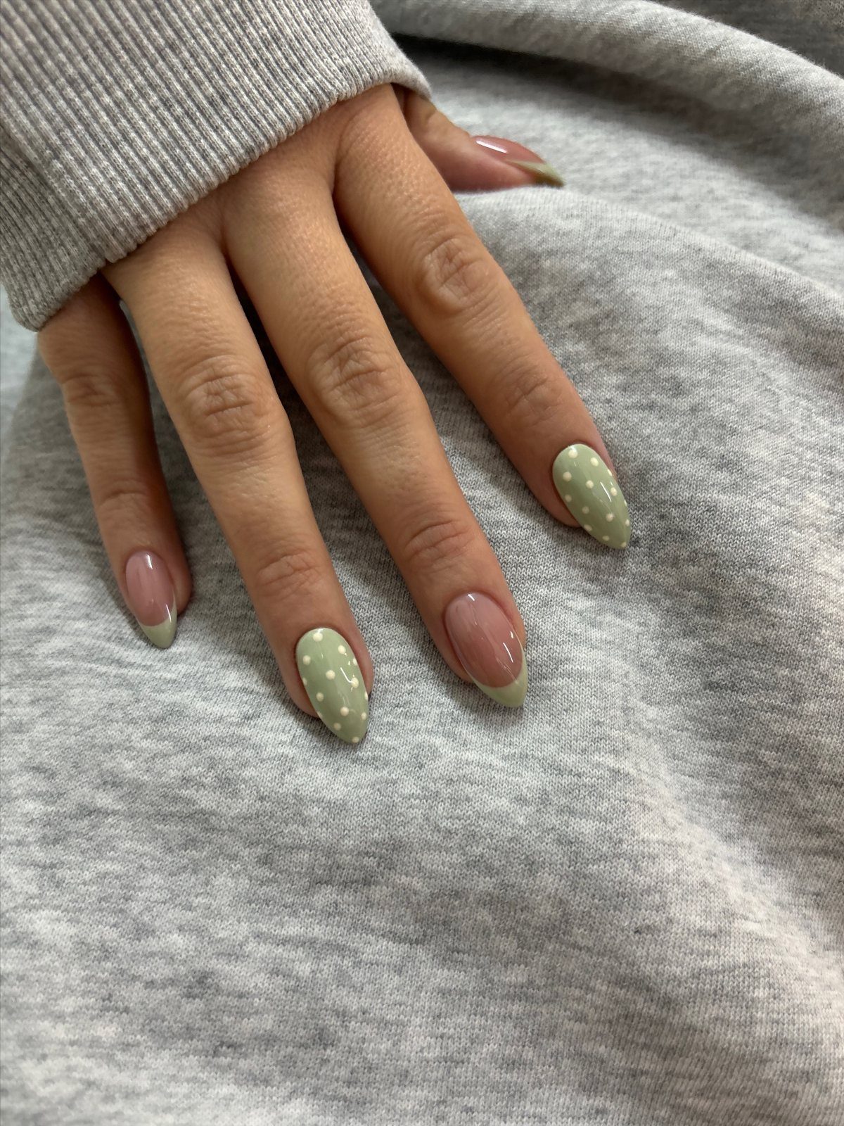 Almond nails with pastel lime green polka dots and green French tips.