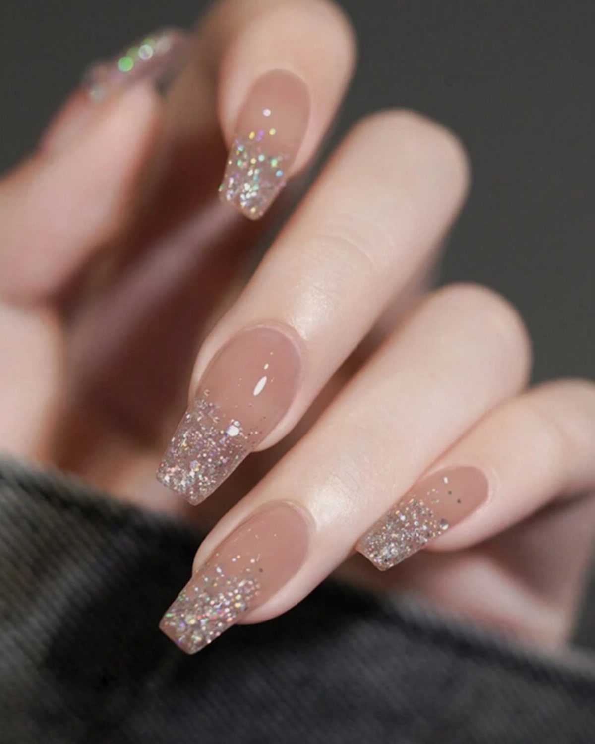 Nude coffin nails with shimmering silver glitter tips in a gradient effect.