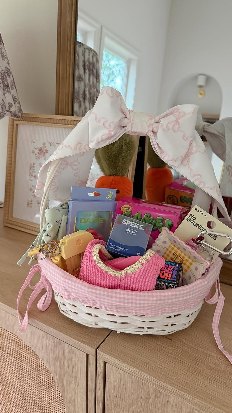White wicker Easter basket with pink gingham lining filled with various colorful gifts.
