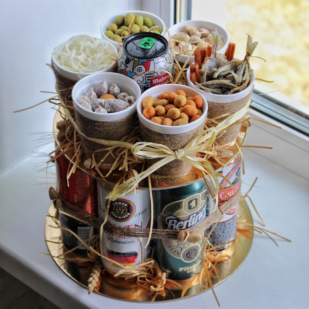 Beer can gift tower topped with bowls of savory snacks and tied with twine.