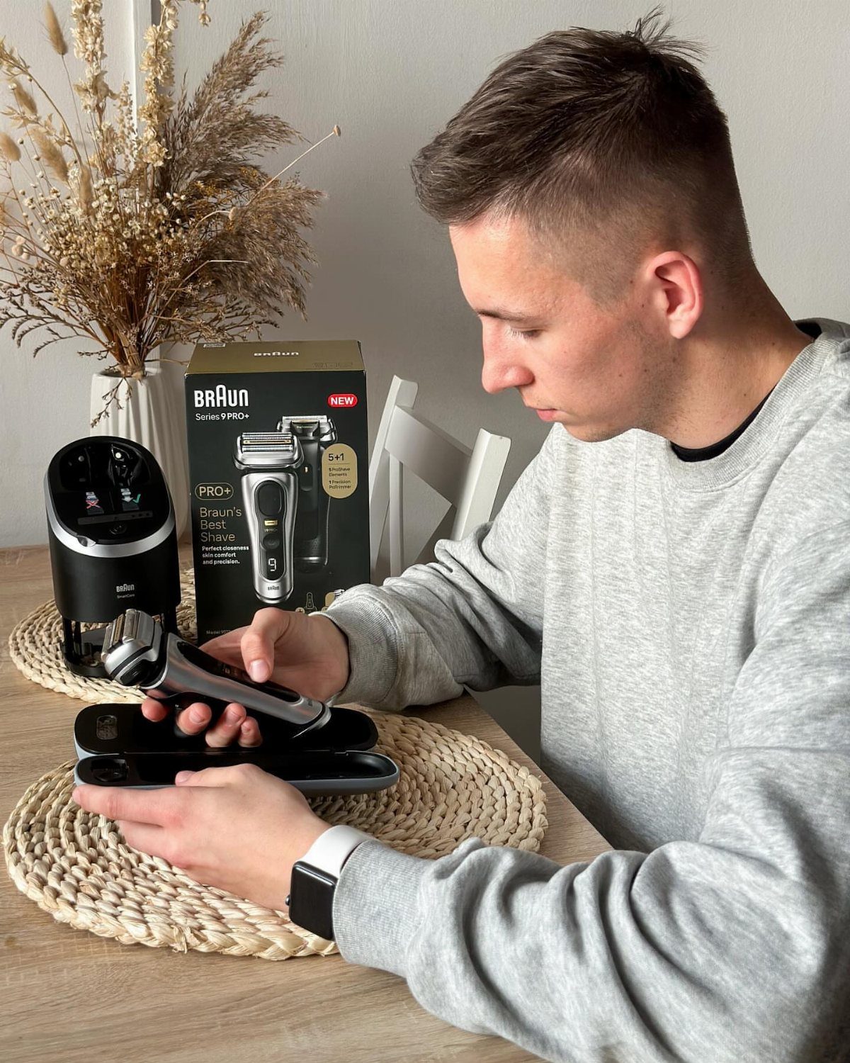 Man holding a Braun Series 9 Pro electric shaver over its charging base.