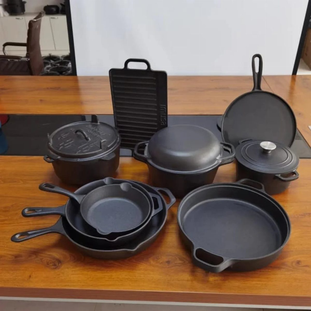 Cast iron cookware set including pots and skillets on a wooden table