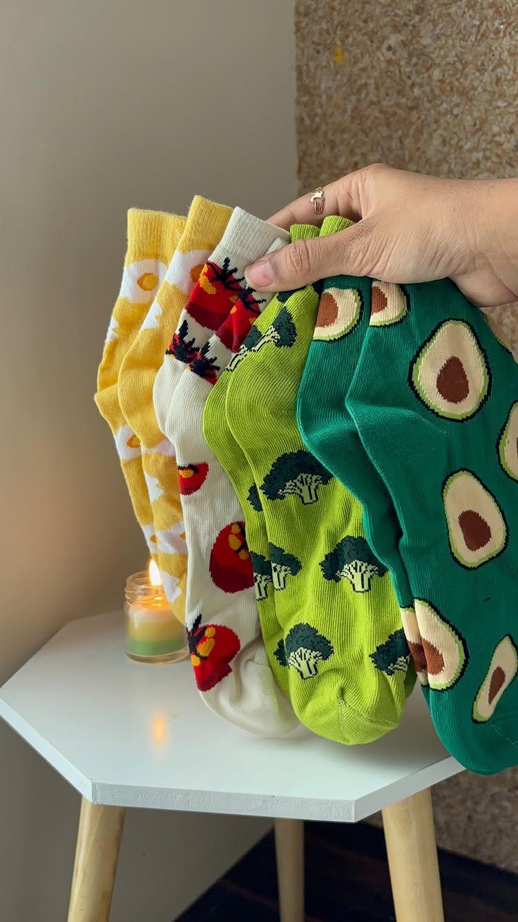 Colorful patterned socks held by a hand over a white table with a candle.