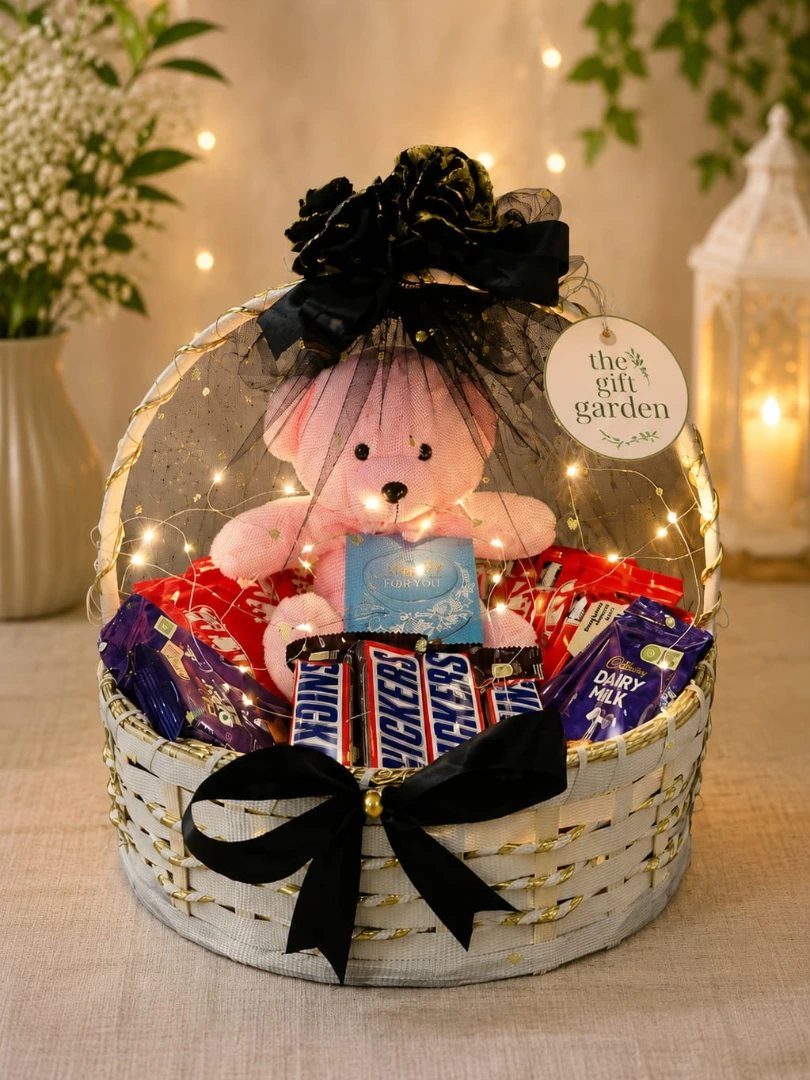 White woven gift basket with a pink teddy bear and assorted chocolate bars.