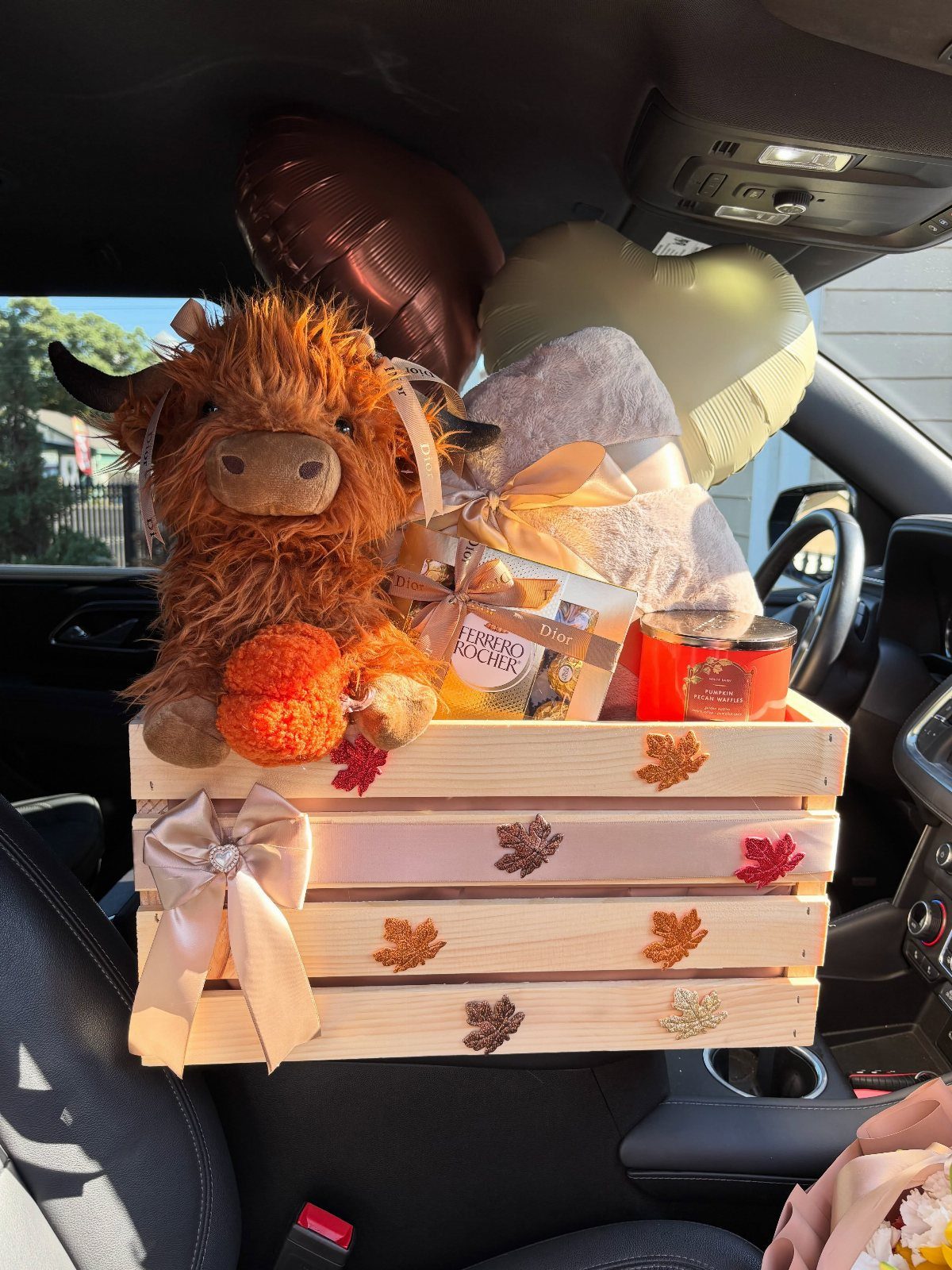 Gift basket in a wooden crate with a plush cow and heart balloons.