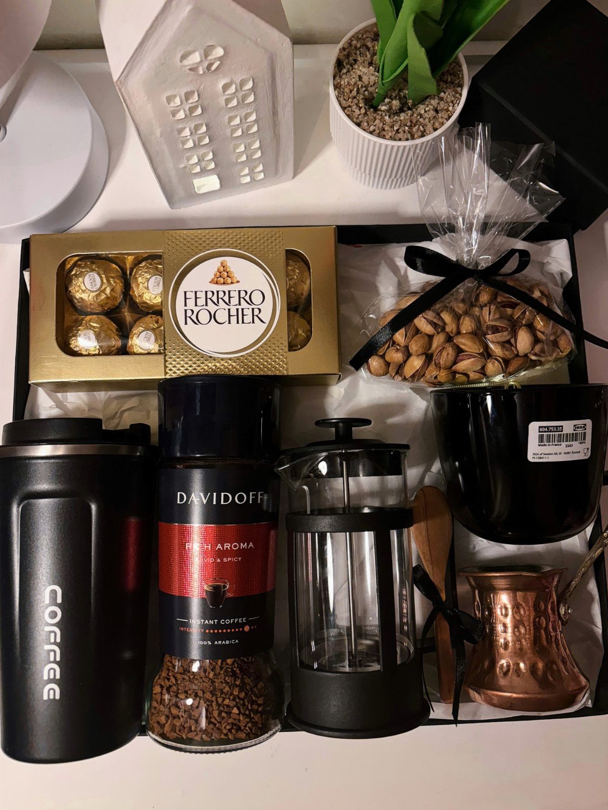 Coffee gift basket with French press, travel mug, coffee jar, and chocolates.