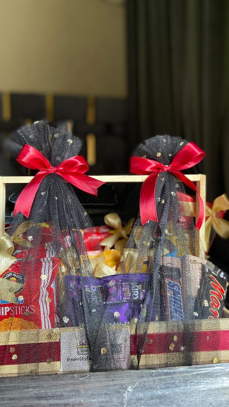 Wooden gift crate filled with snacks and candies decorated with red bows