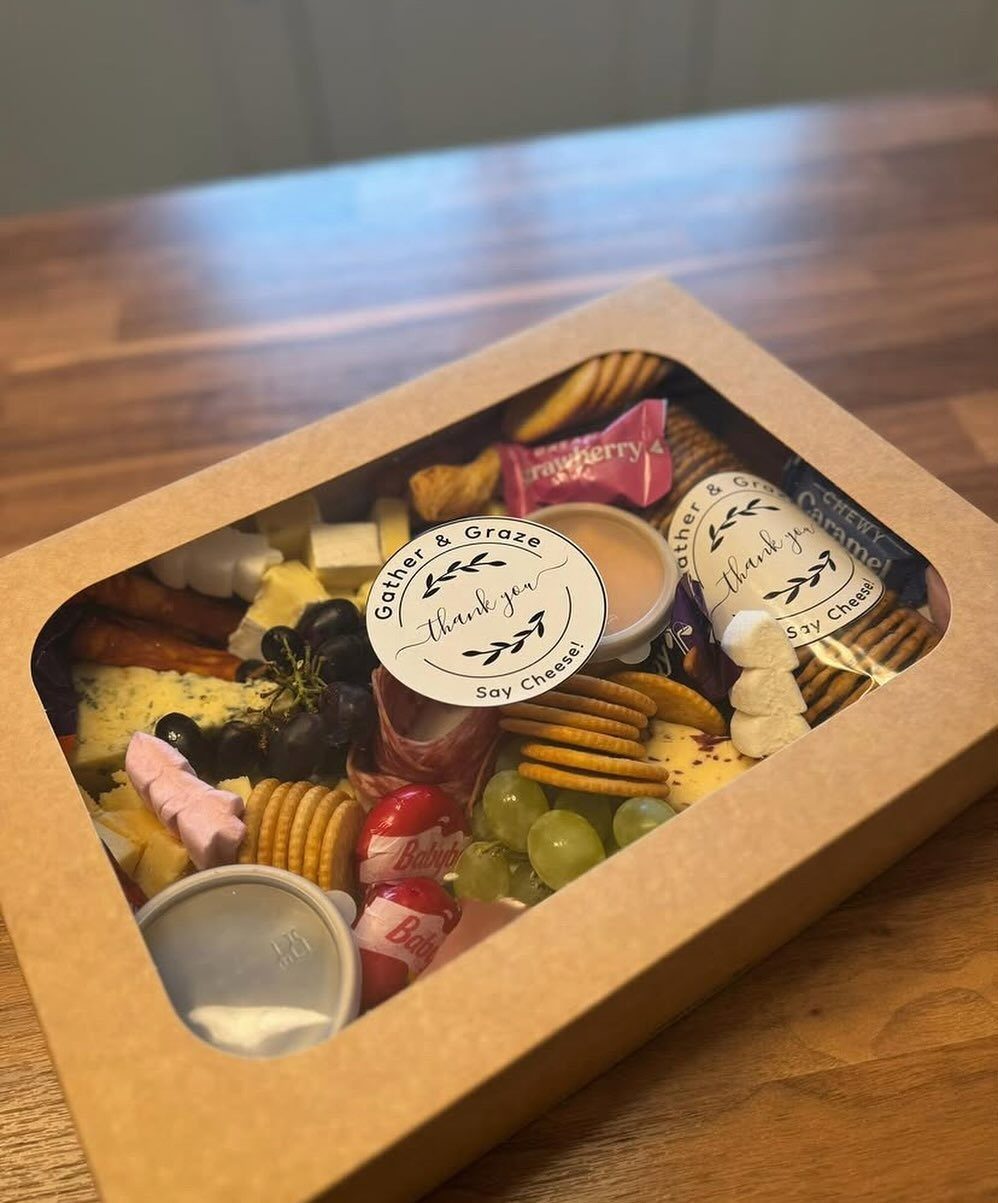 Gourmet meat and cheese gift box with grapes and crackers on wooden table