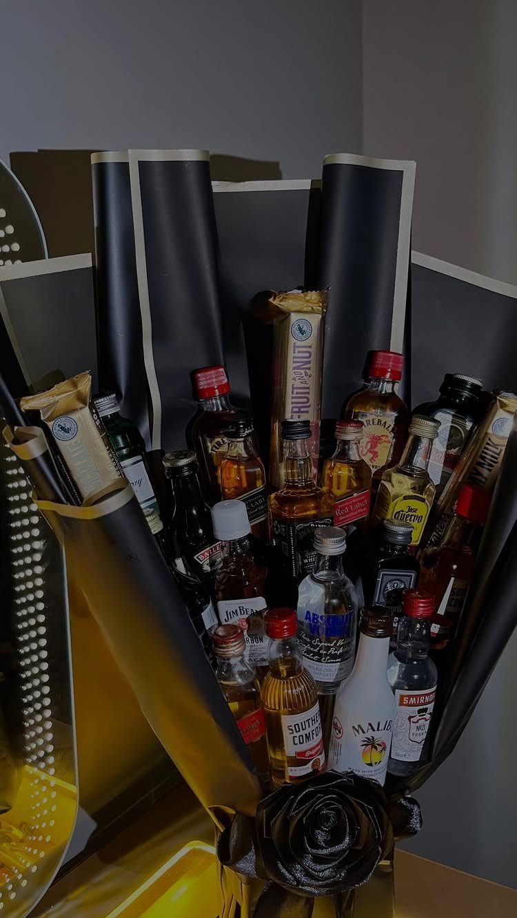 Gift bouquet of miniature alcohol bottles and snacks wrapped in black and gold paper