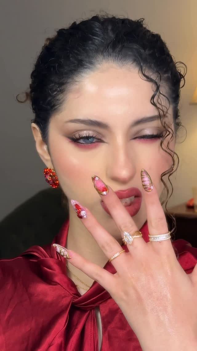 Woman with red eyeshadow and lipstick wearing red satin and themed nail art.