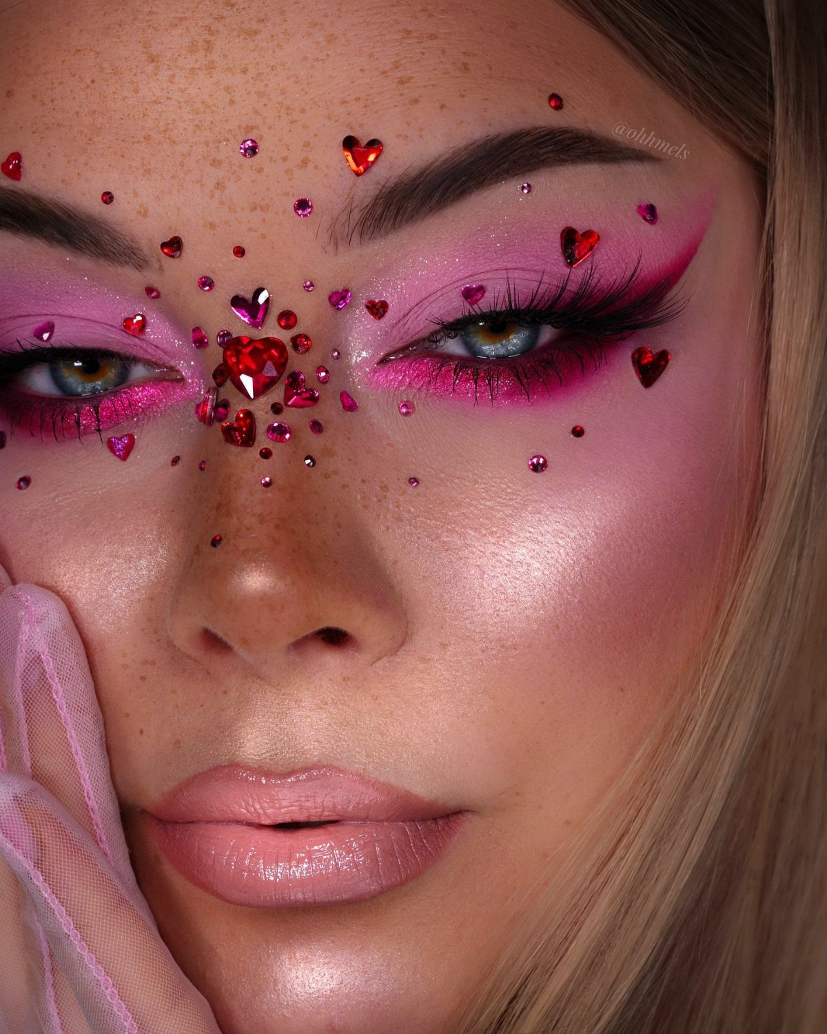 Woman with monochromatic pink makeup and red heart gems around her eyes