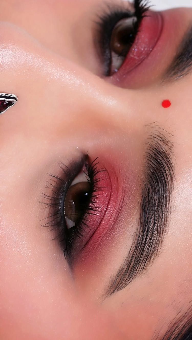 Close-up of eyes with blended pink and red smoky eyeshadow and defined brows.