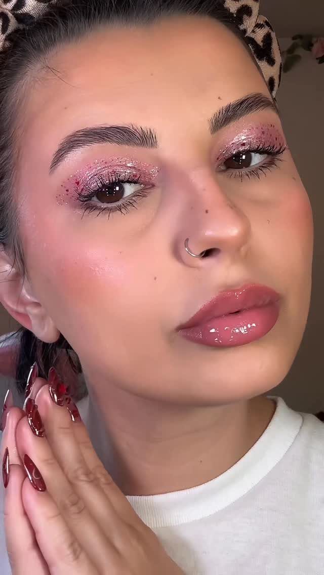 Woman with glittery pastel pink eyeshadow, glossy pink lips, and a leopard headband.