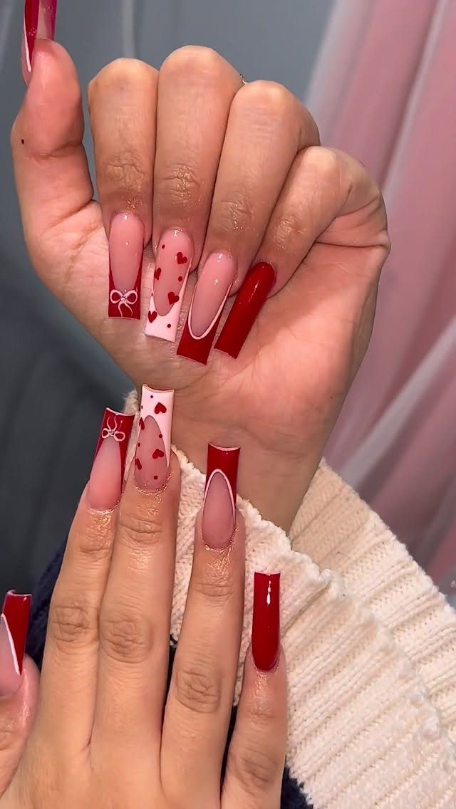 Square acrylic nails with red and white Valentine's Day heart and bow designs.