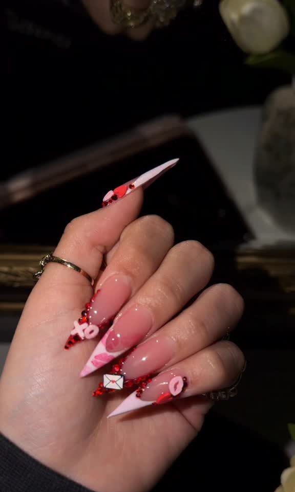 Stiletto nails with nude base, white tips, red hearts, and lip art.