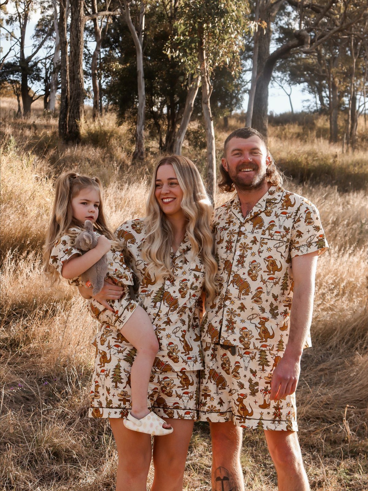 Family wearing matching cream and brown animal print loungewear sets in a field.
