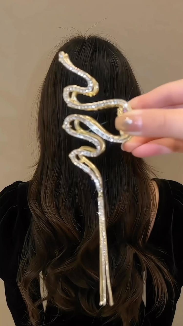 Gold wavy hair clip with crystals held against long brown hair