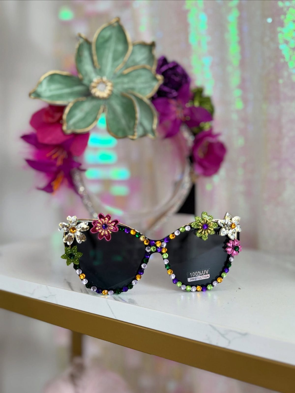 Decorated cat-eye sunglasses with colorful rhinestones and flowers on a marble surface