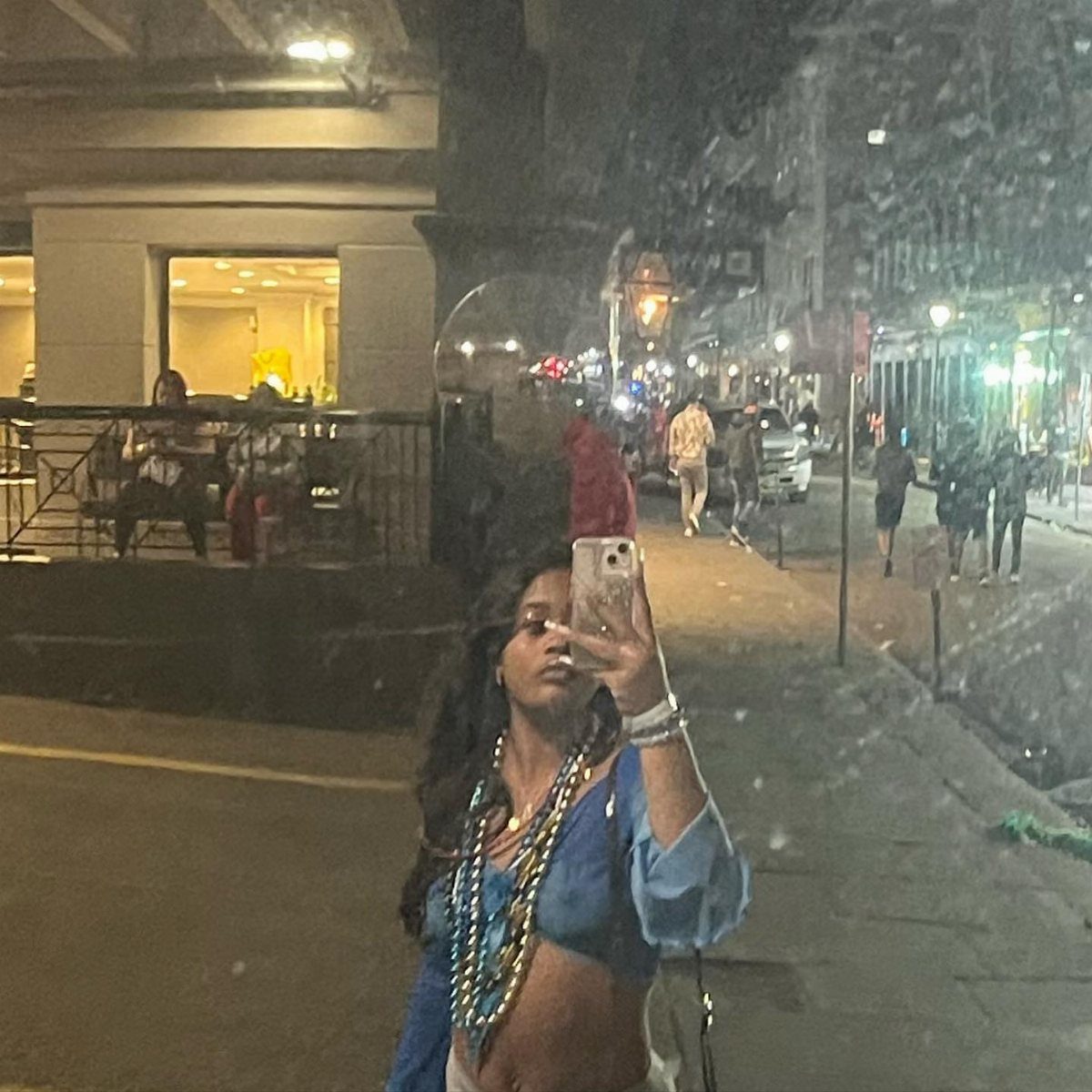 Woman wearing multiple layers of gold and blue beads on a city street.