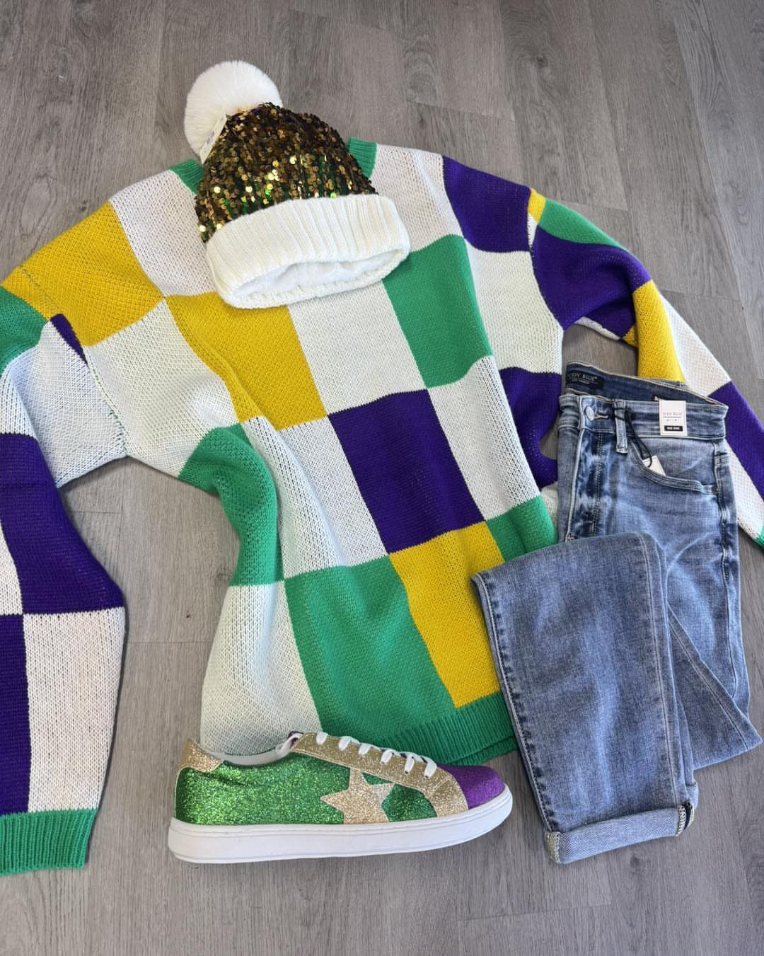 Mardi Gras outfit featuring a colorful checkered sweater, blue jeans, and glittery accessories.