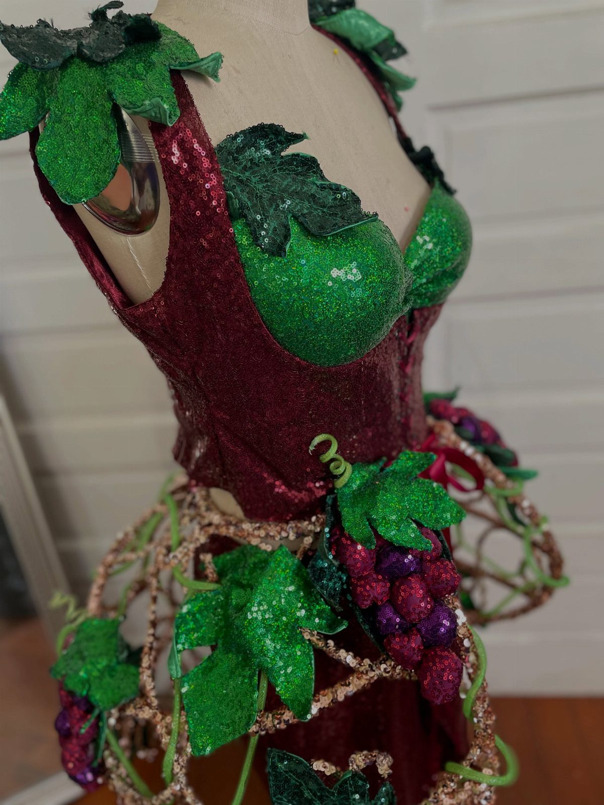 Grape-themed costume on a mannequin with burgundy glitter and green glittery leaves.