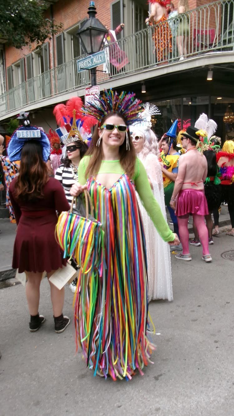 Woman in a colorful ribbon dress and feathered headpiece at a parade.