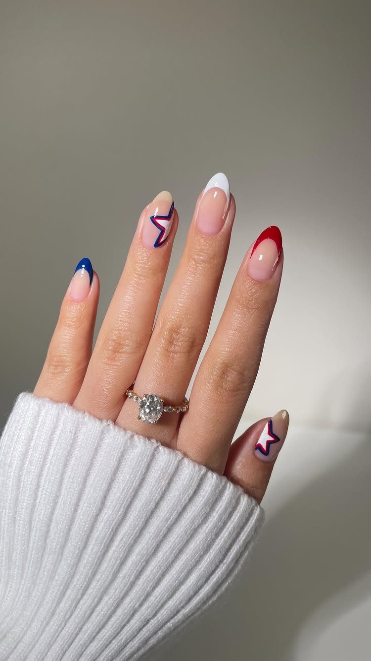 Almond nails with red, white, and blue tips and star patterns on nude base.